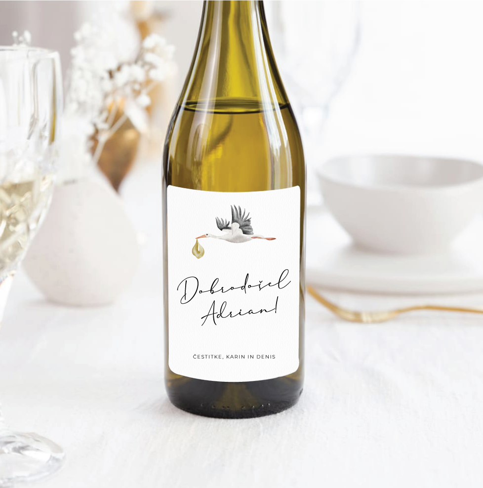Personalizirana vinska etiketa s štorkljo in napisom »Dobrodošel Adrian« na steklenici belega vina.